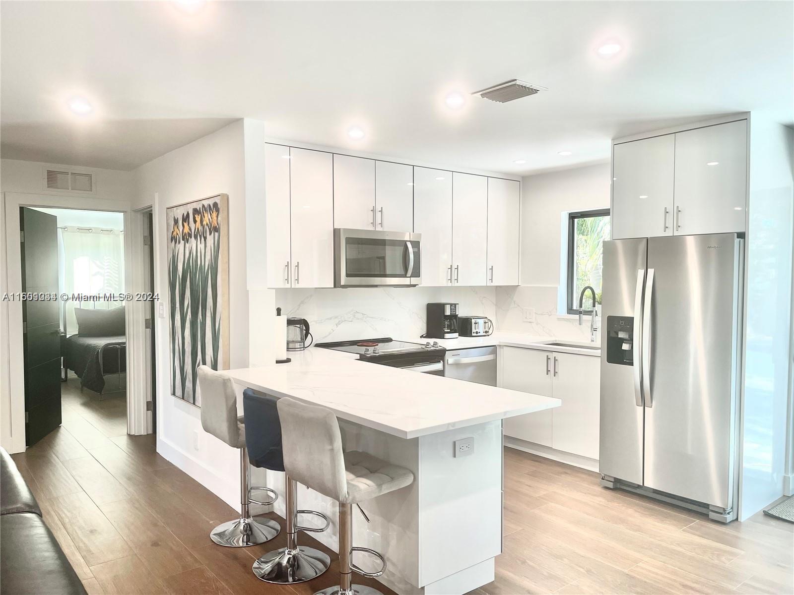 a kitchen with a refrigerator a stove cabinets and wooden floor