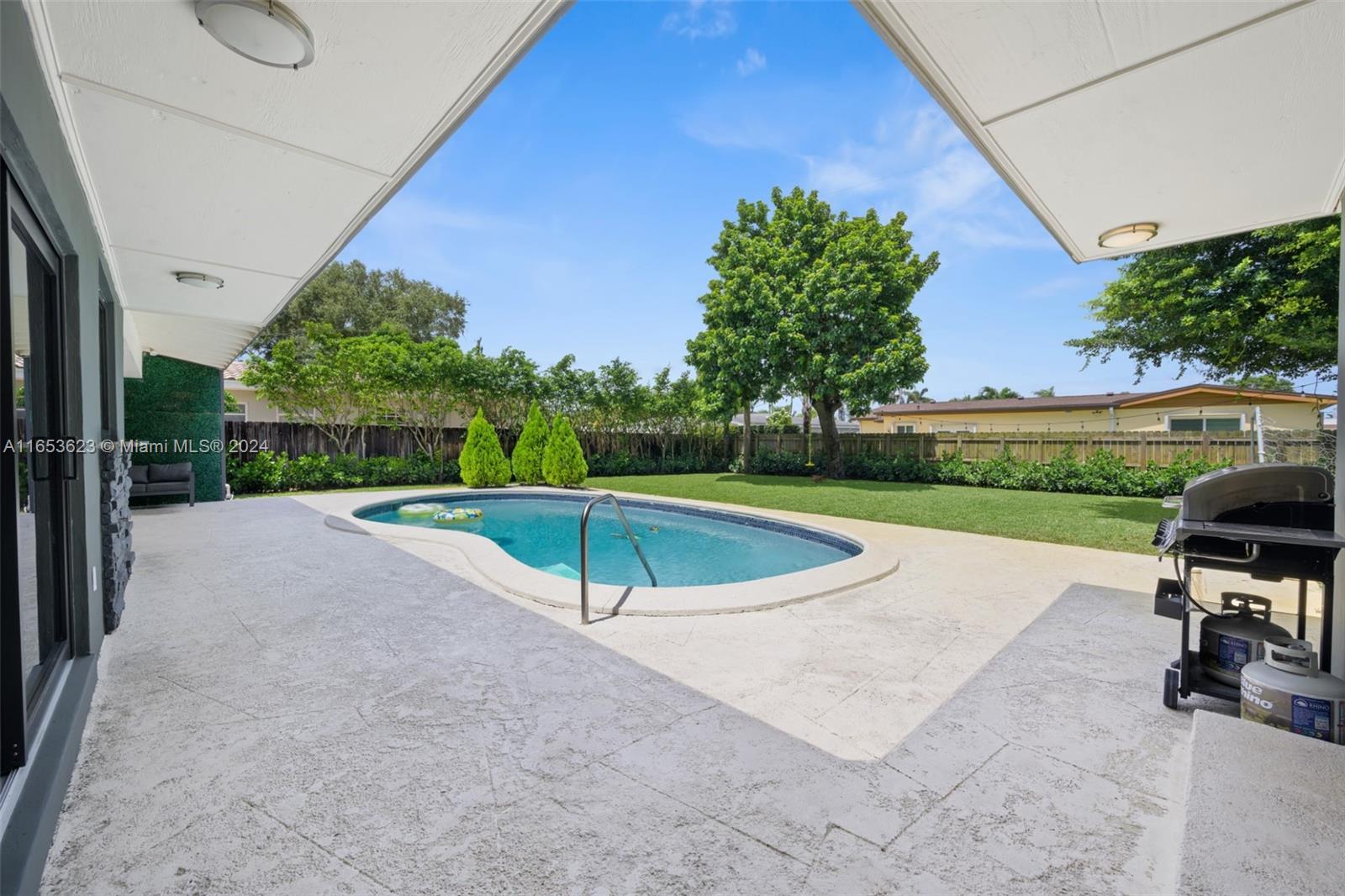 a view of a swimming pool with lawn chairs and a big yard