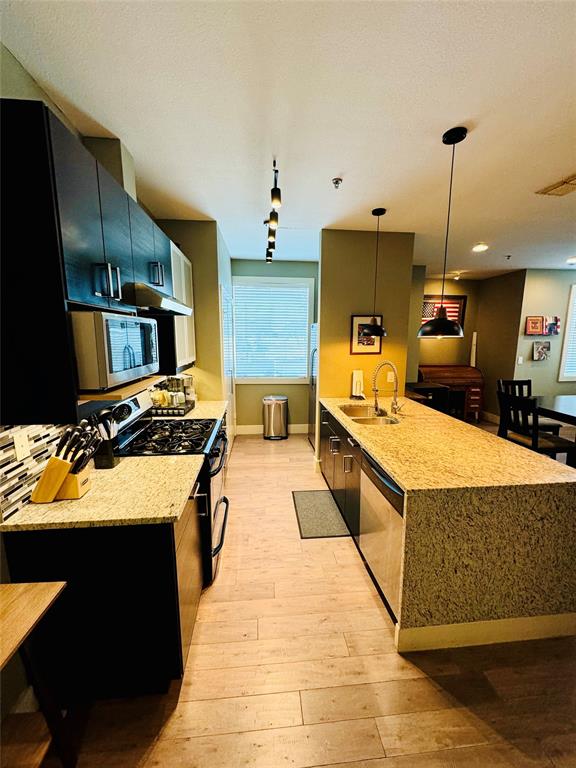 a large kitchen with stainless steel appliances granite countertop a stove a sink dishwasher and a refrigerator with wooden floor