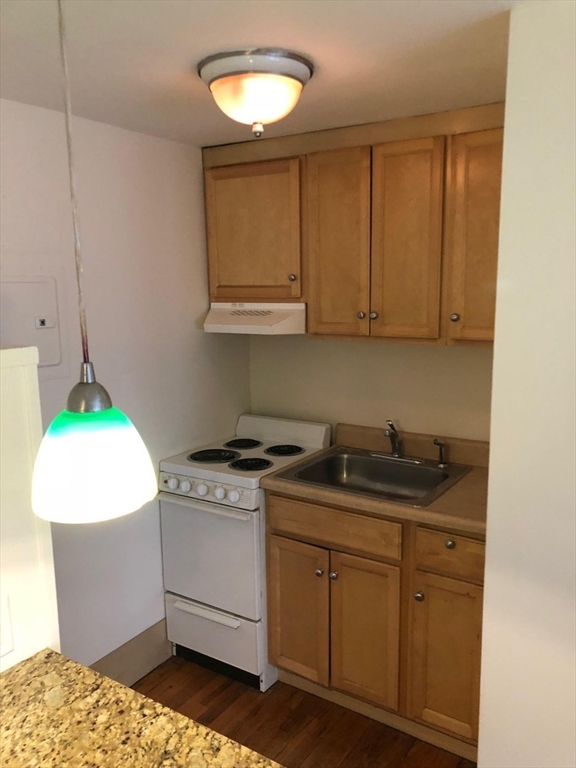 a kitchen with granite countertop a sink a stove and cabinets