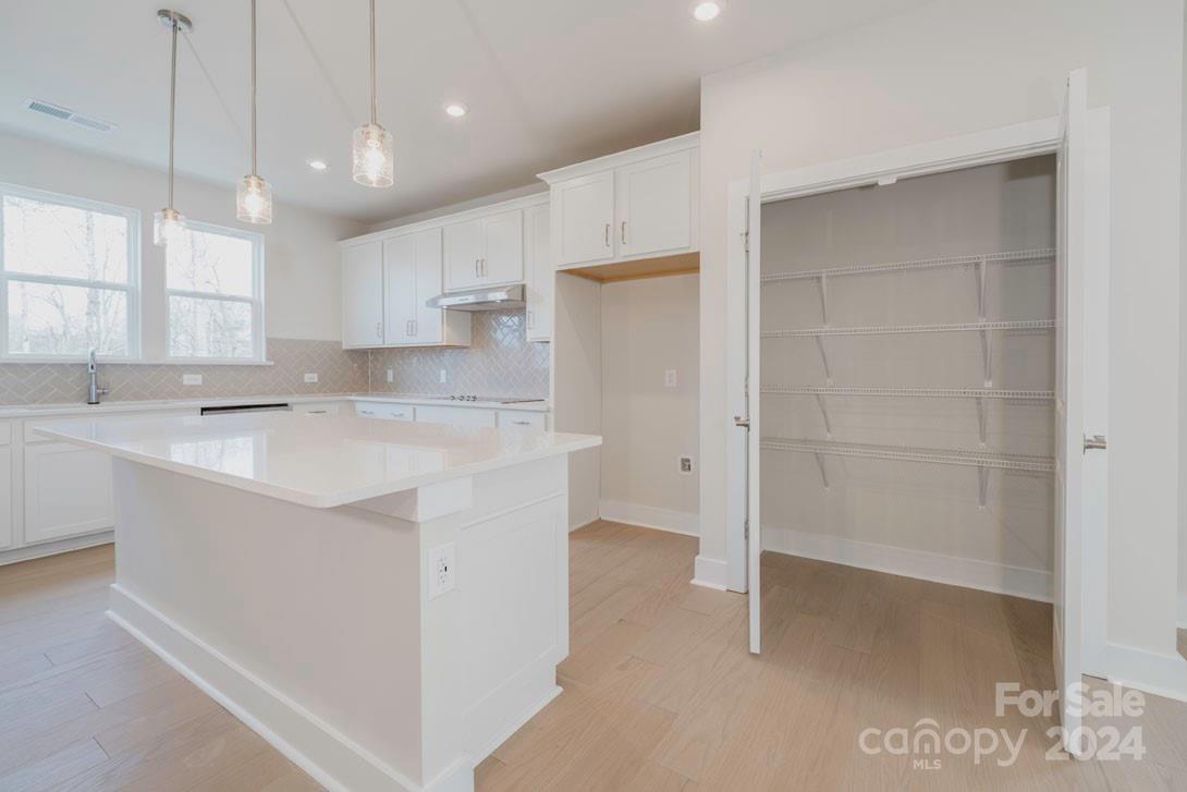 a kitchen with kitchen island a sink stainless steel appliances and white cabinets