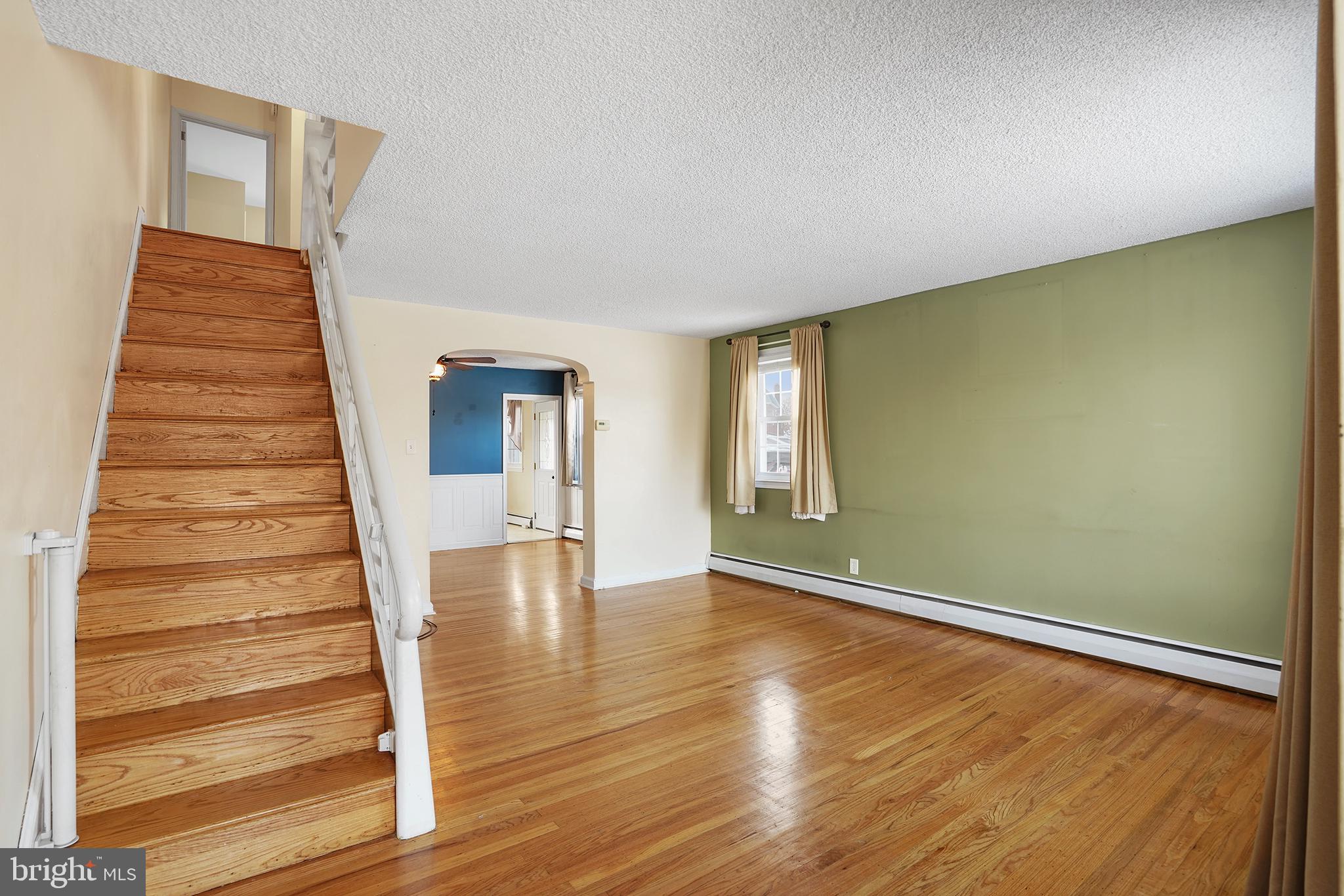 a view of an empty room with wooden floor and stairs