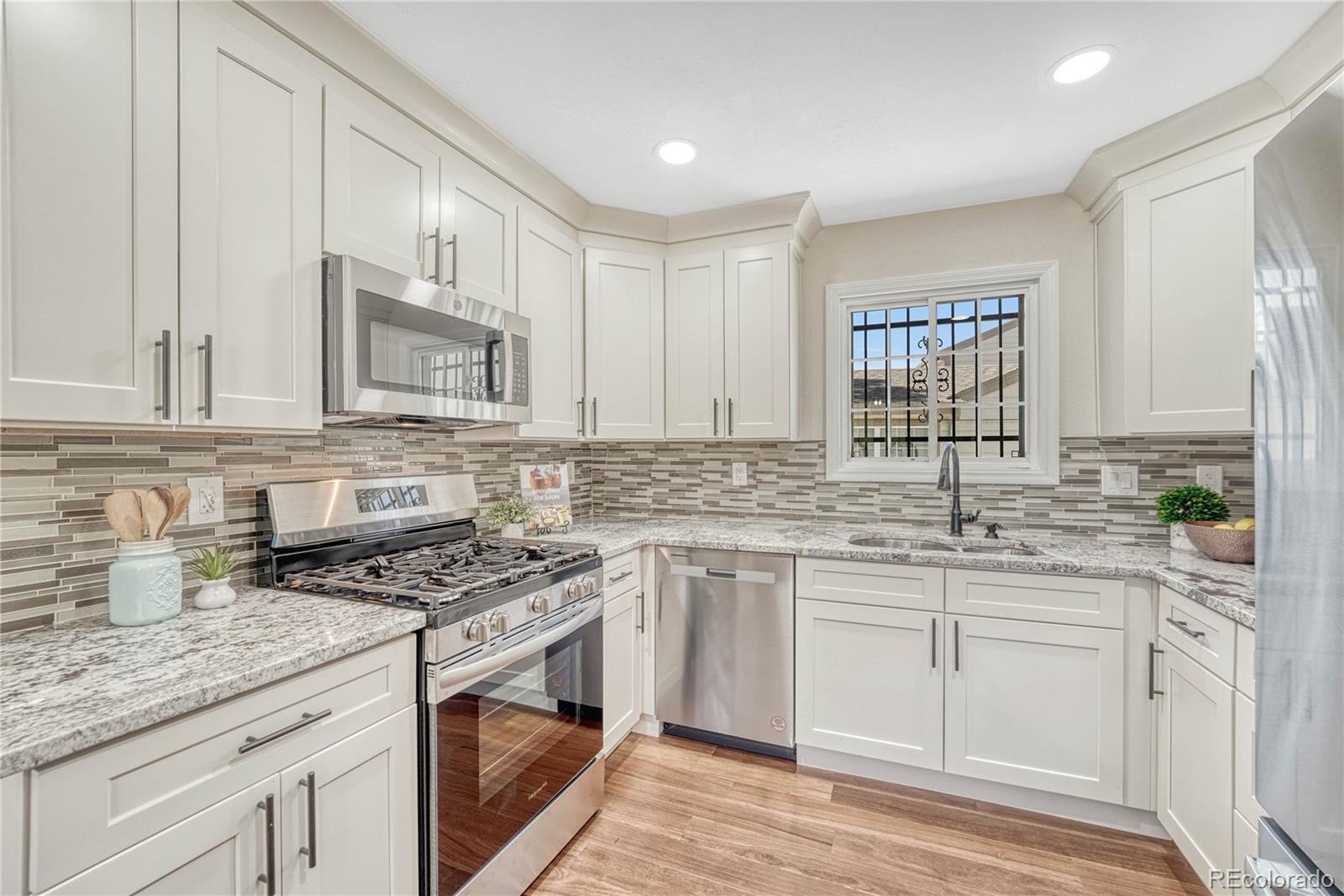 a kitchen with white cabinets sink and appliances