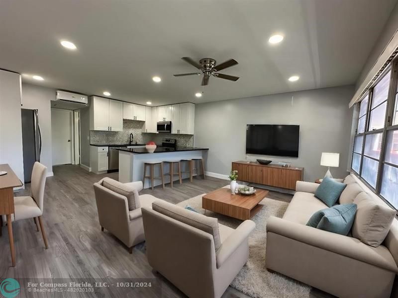 a living room with furniture kitchen and a flat screen tv