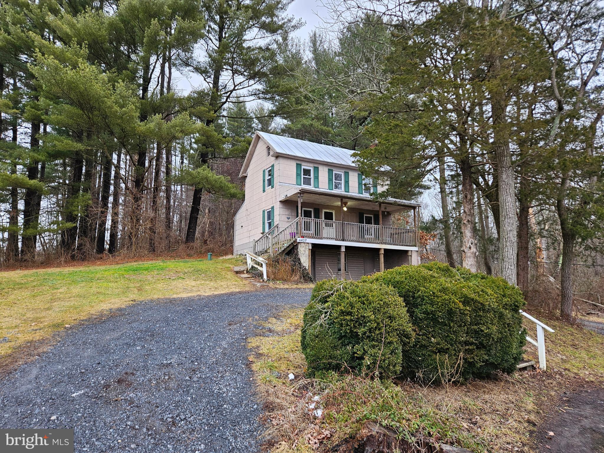 a view of a house with a yard and large trees