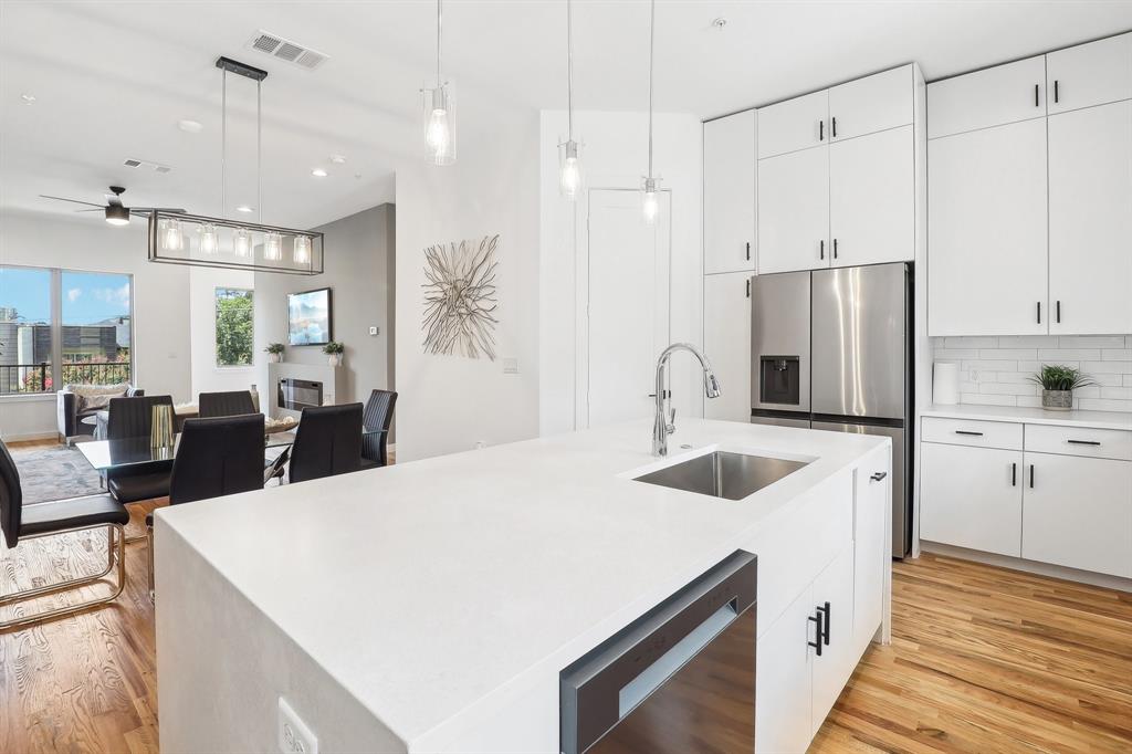 a large white kitchen with a sink and refrigerator