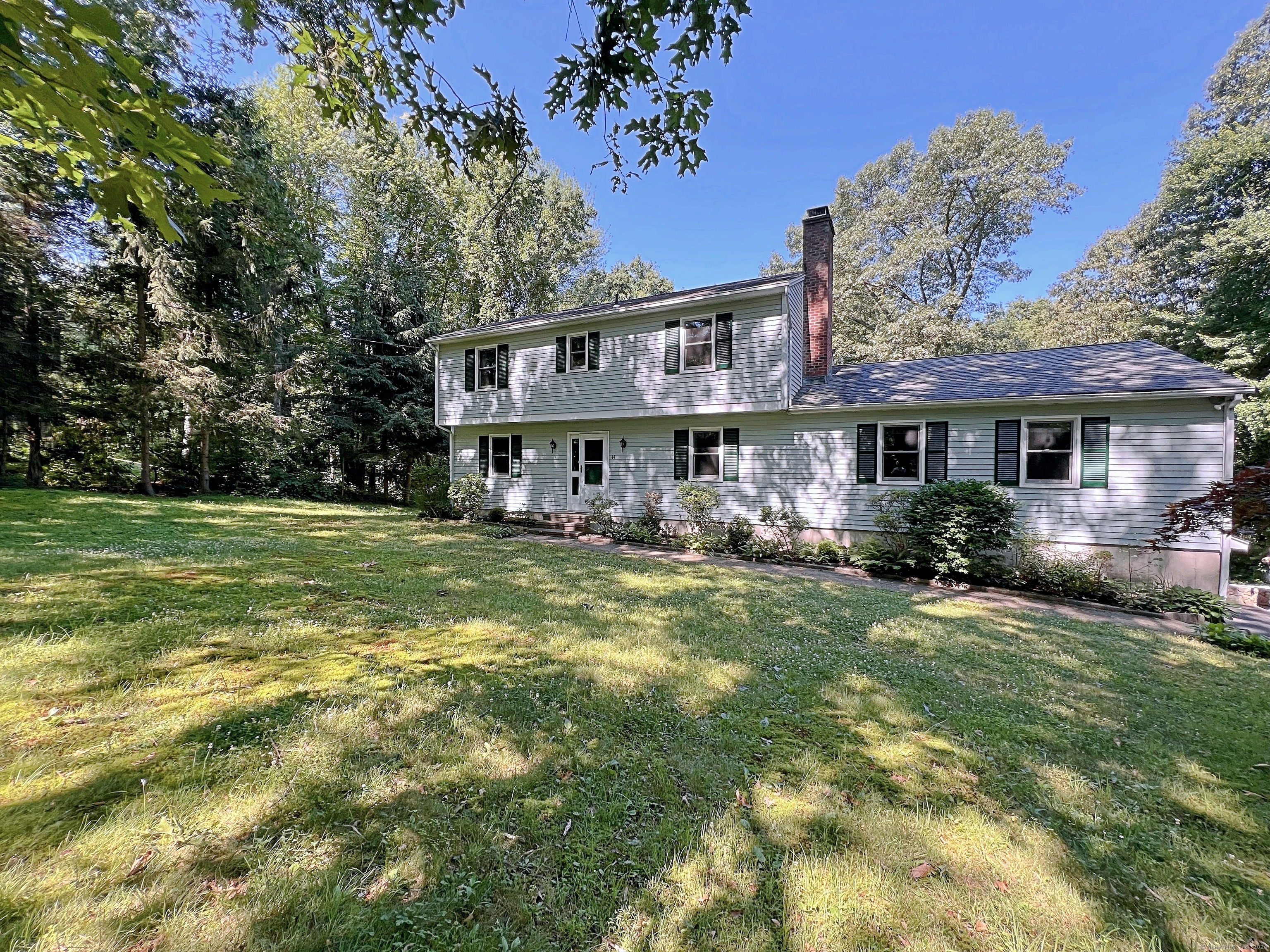 a view of a house with a big yard plants and large trees