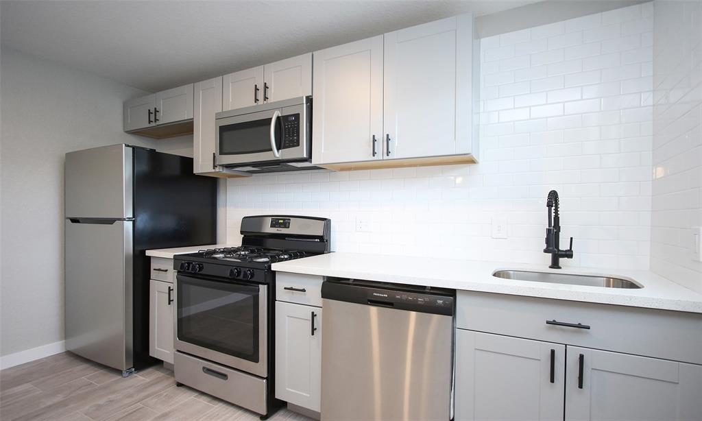 a kitchen with stainless steel appliances granite countertop white cabinets a stove a microwave and a refrigerator