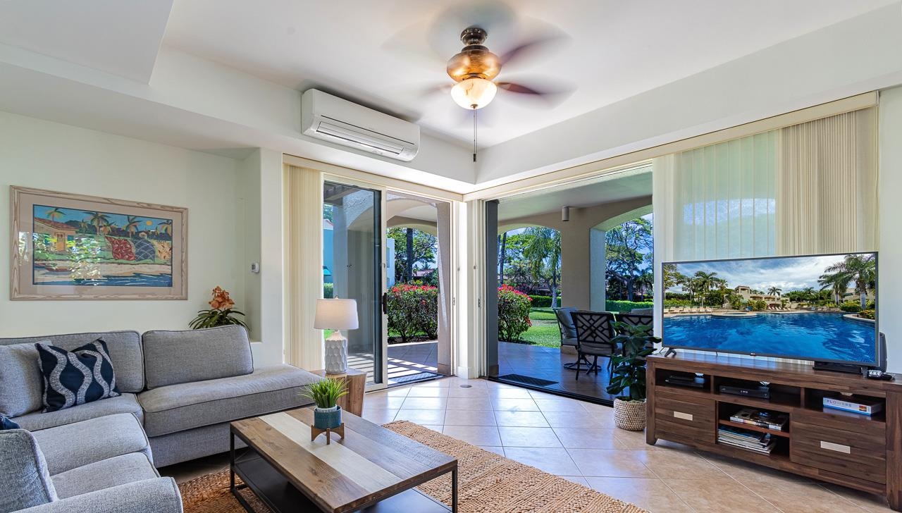 covered lanai surrounded by tropical landscaping & a manicured lawn.