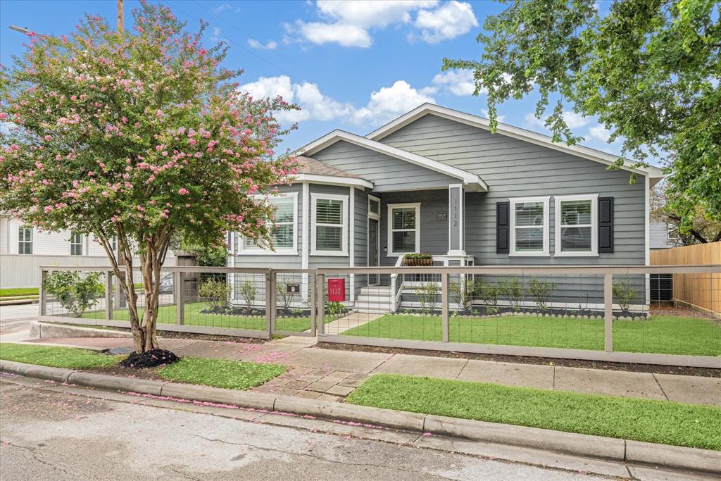 This stunning gray craftsman-style home boasts a welcoming front porch and lush landscaping.