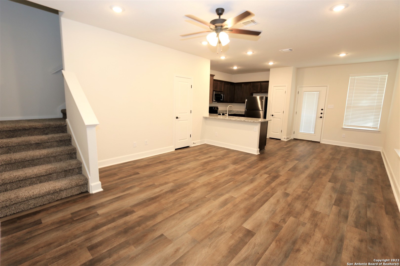 a view of a kitchen with wooden floor and a ceiling fan