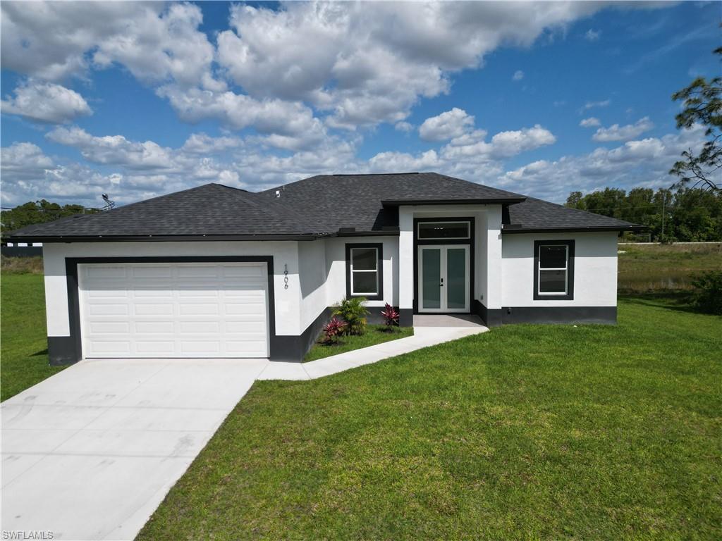 View of front facade with a front yard, french doors, and a garage