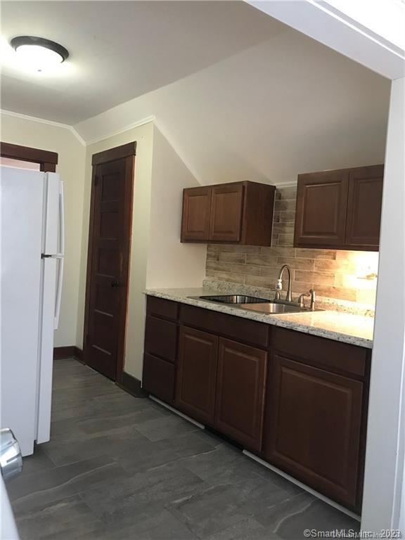 a kitchen with granite countertop wooden cabinets and refrigerator