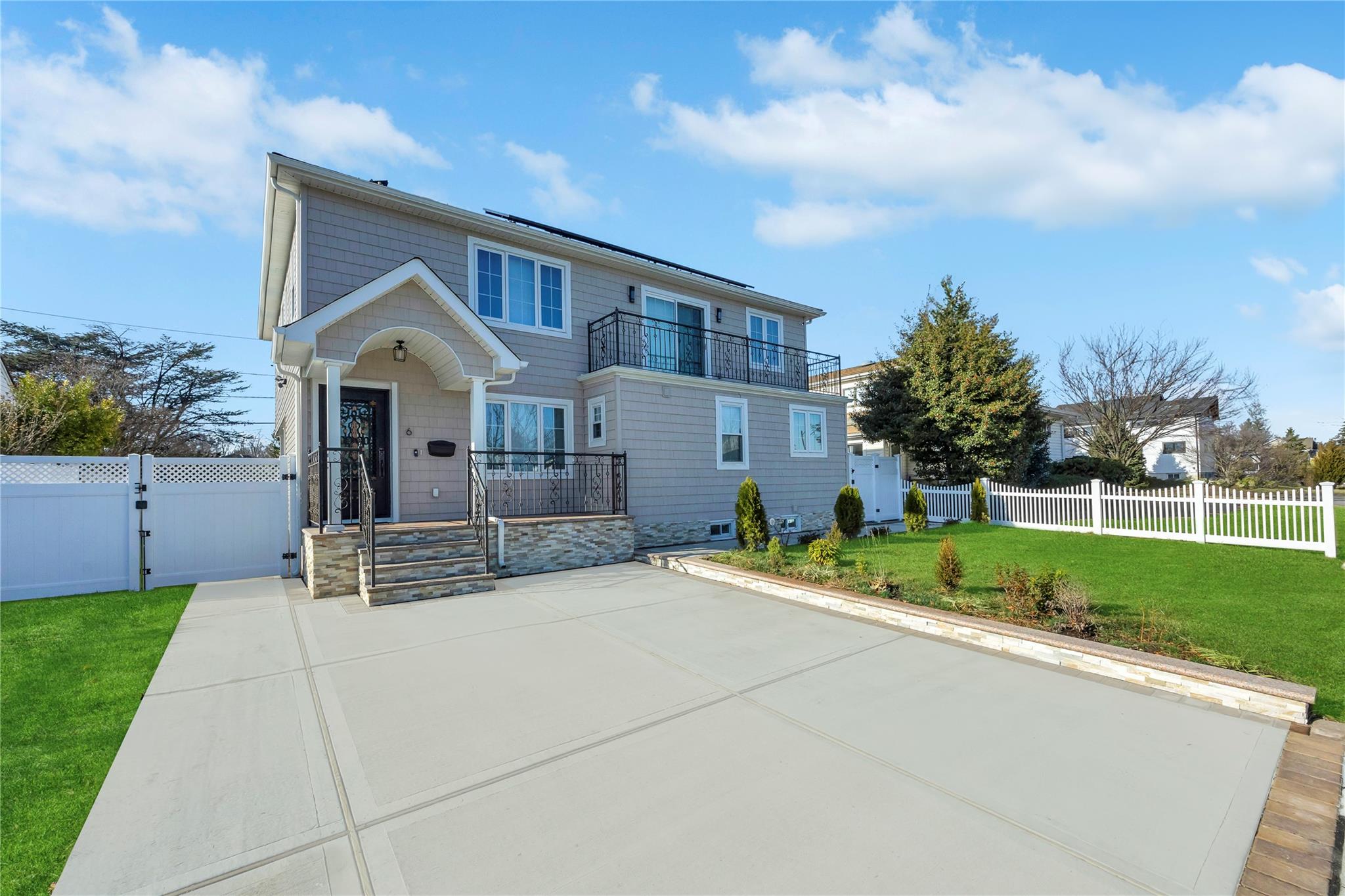 View of front of property with a balcony and a front yard