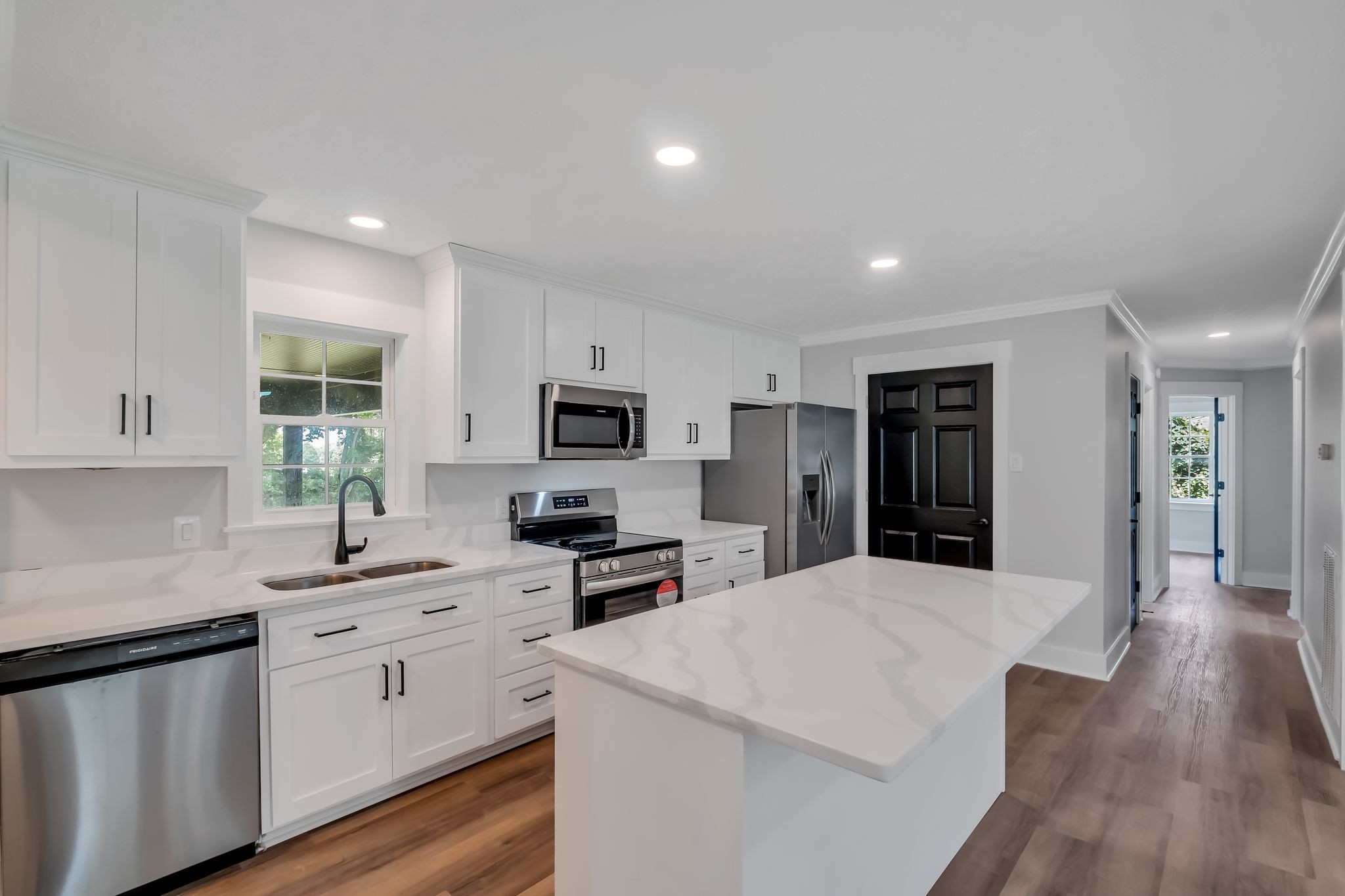 a kitchen with white cabinets a sink stove and refrigerator