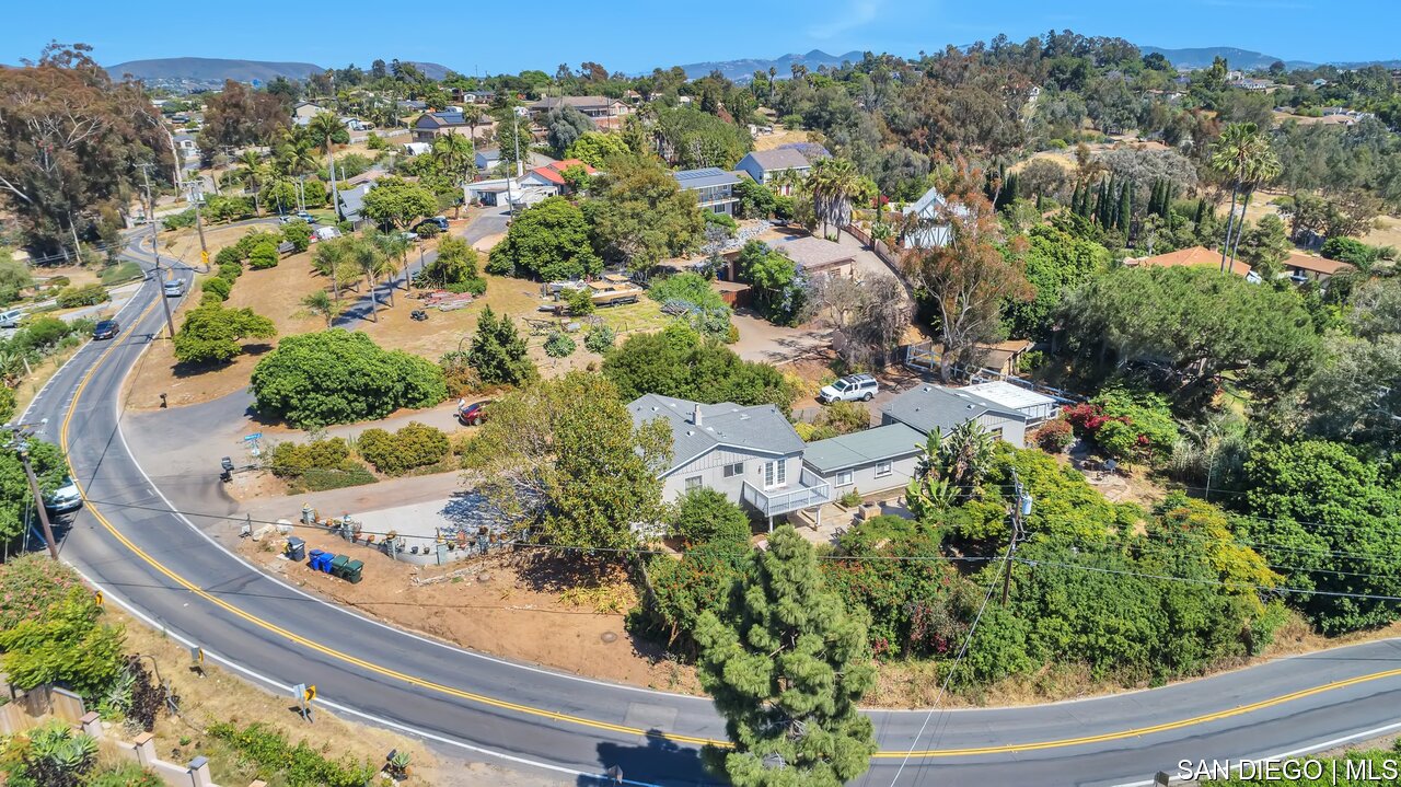 an aerial view of a house with a yard lake and mountain view in back