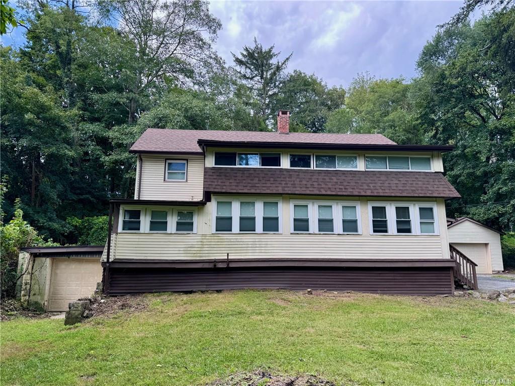 View of front of home featuring a front lawn, an outbuilding, and a garage