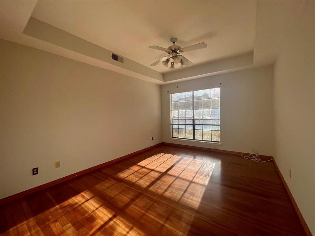 a view of empty room with wooden floor and fan