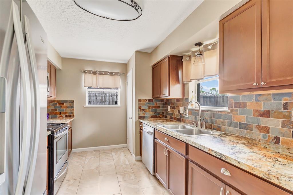 a kitchen with granite countertop a sink stove and refrigerator