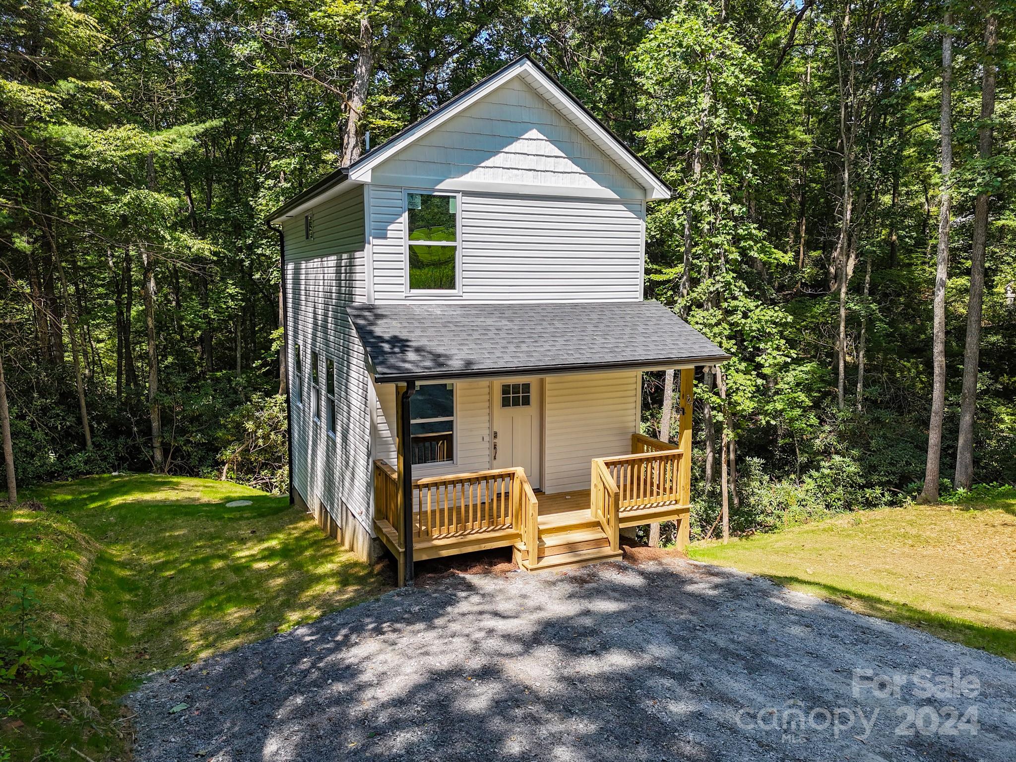 a front view of house with yard and trees in the background