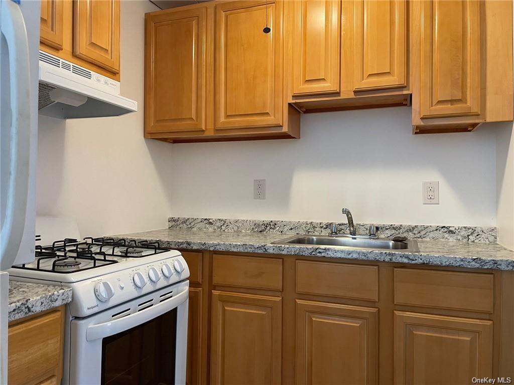 a kitchen with granite countertop stainless steel appliances white cabinets and a sink