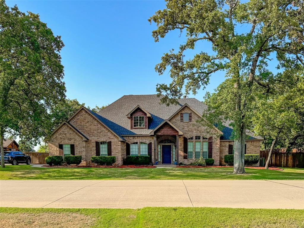 a front view of a house with a yard and large trees