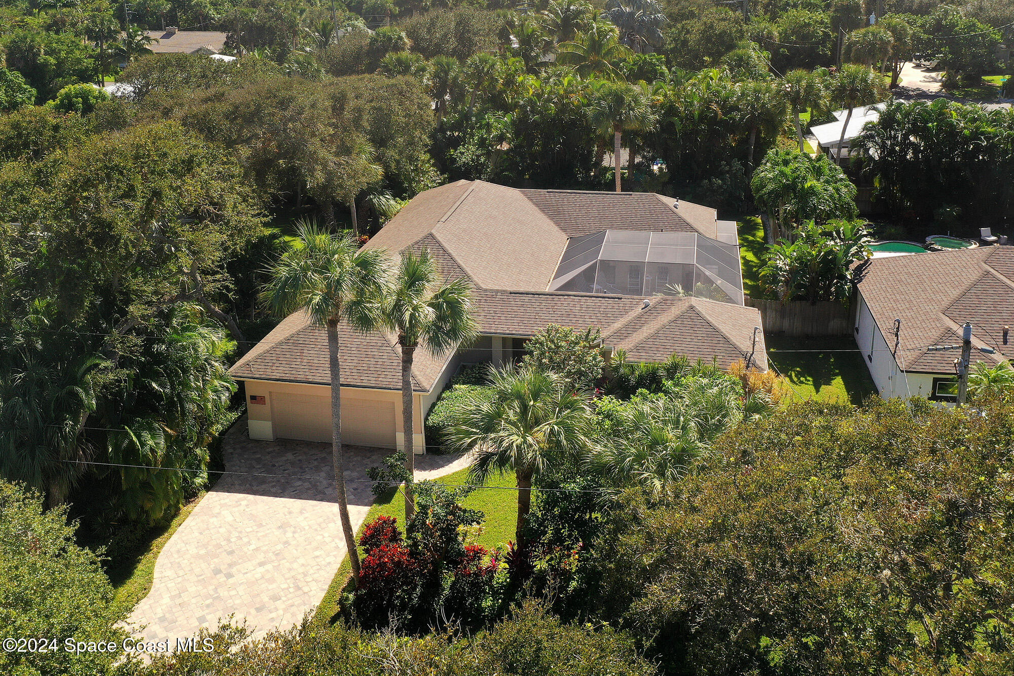 an aerial view of a house with a yard and covered with trees