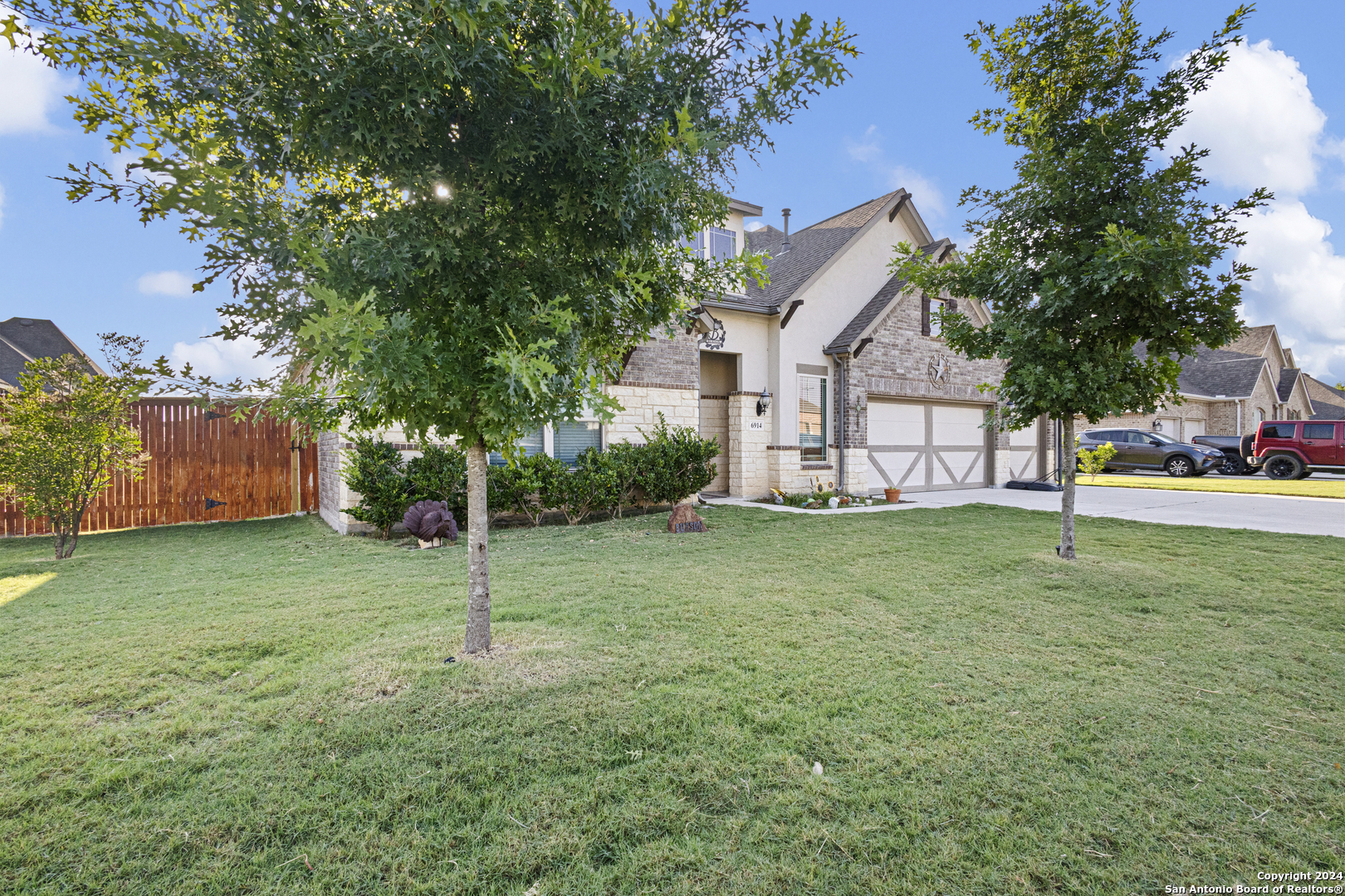 a view of a house with a yard and a large tree