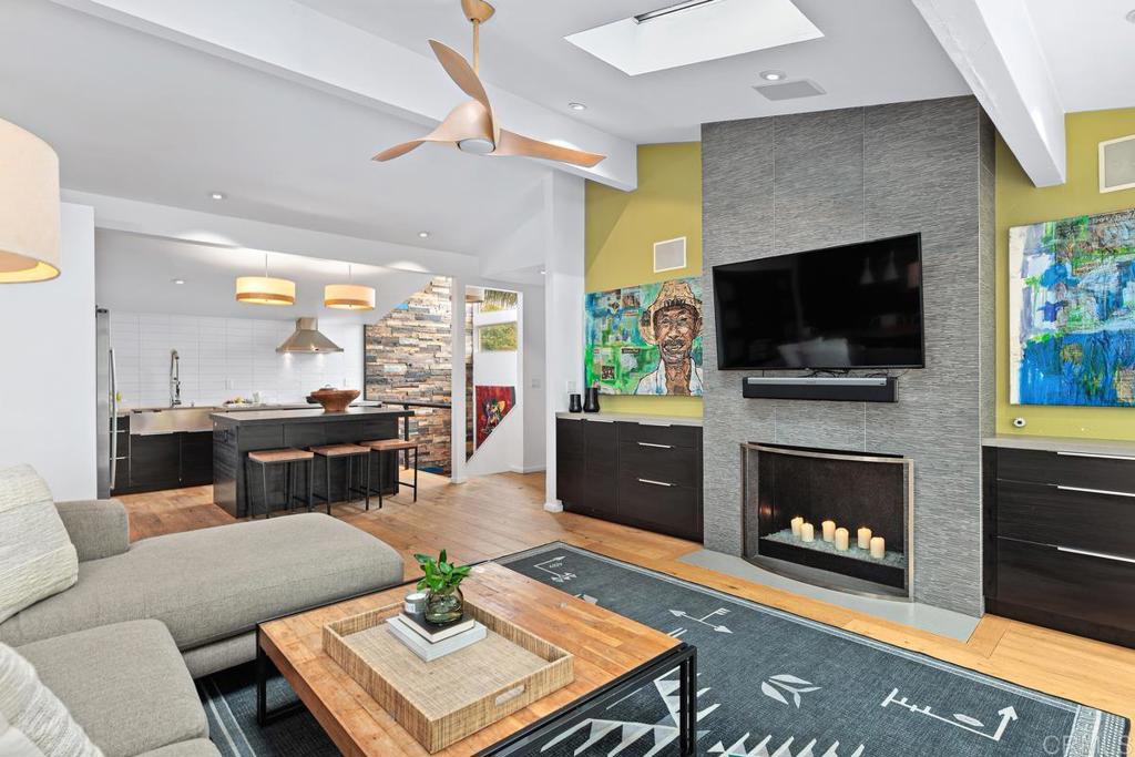 a living room with furniture a fireplace a flat screen tv and kitchen view