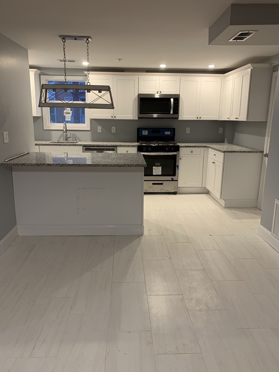 a kitchen with kitchen island white cabinets and appliances