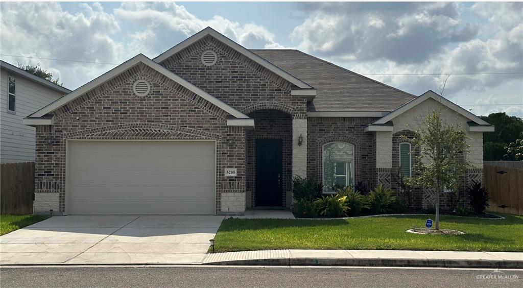 View of front of property with a garage and a front lawn