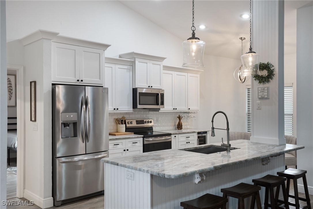 a kitchen with kitchen island a counter space a sink appliances and cabinets