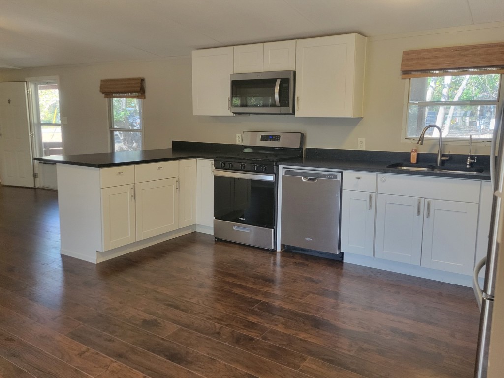 a kitchen with granite countertop a stove a sink and a microwave