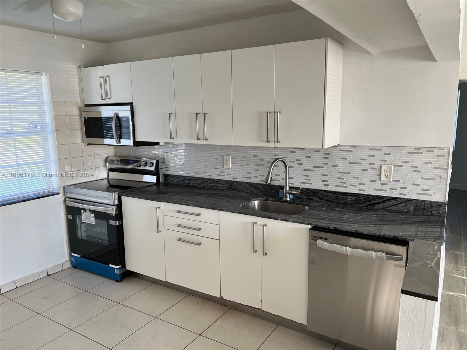 a kitchen with granite countertop white cabinets and stainless steel appliances