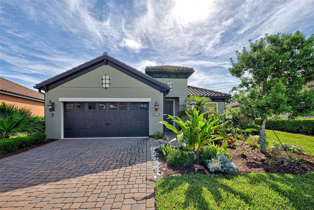 a front view of a house with a yard and a garden