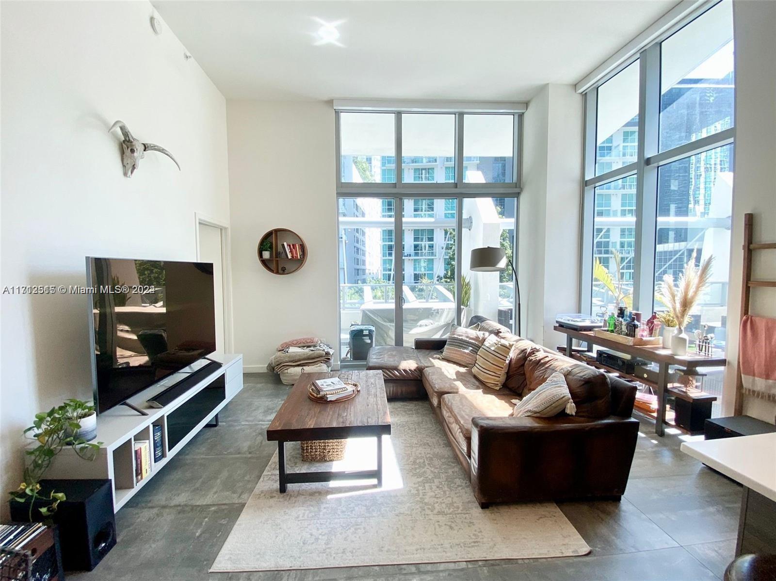 a living room with furniture a flat screen tv and a large window