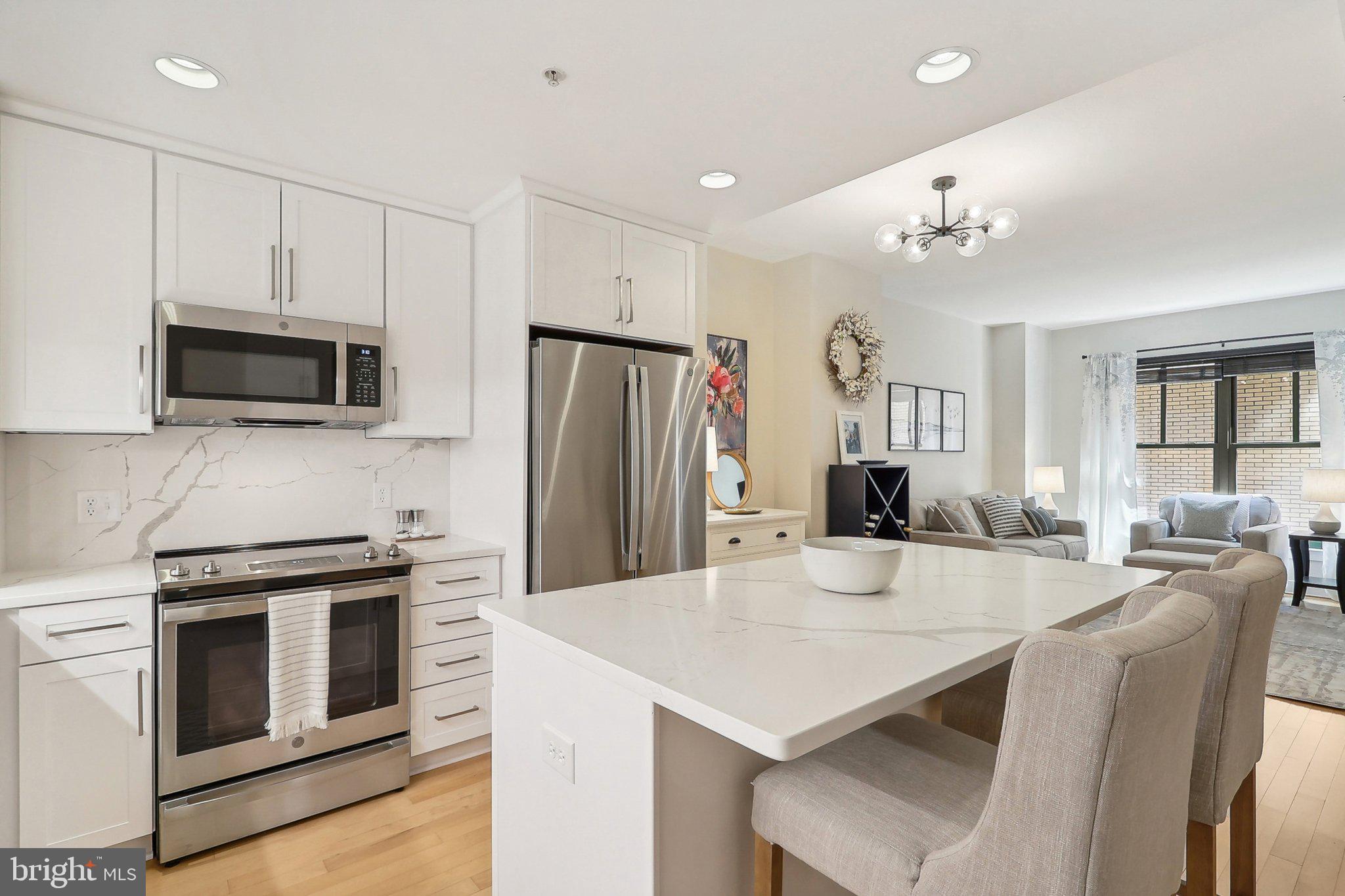 a kitchen with stainless steel appliances kitchen island a table chairs microwave and refrigerator