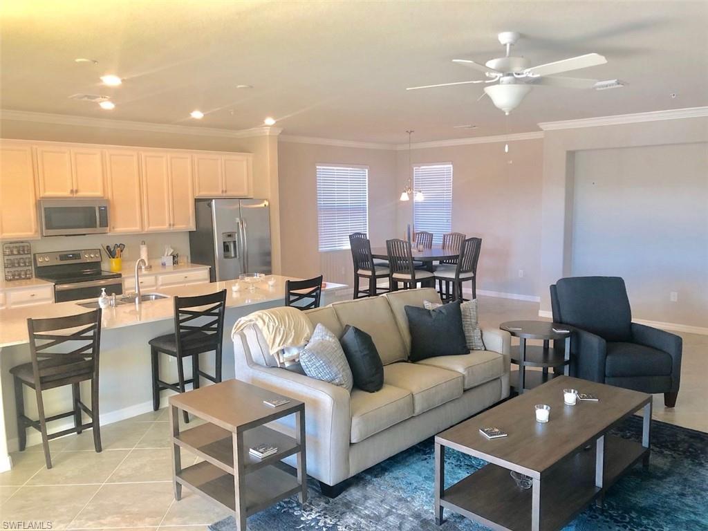 a living room with furniture kitchen view and a chandelier