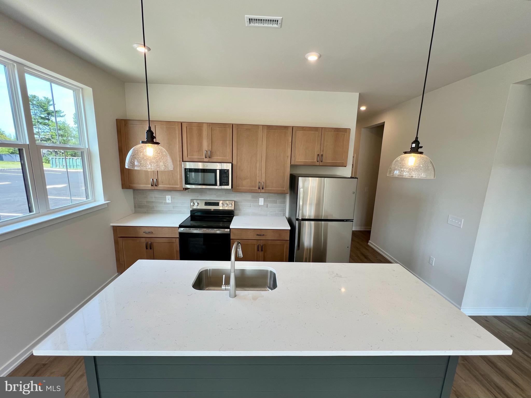 a kitchen with kitchen island a counter space a sink appliances and cabinets