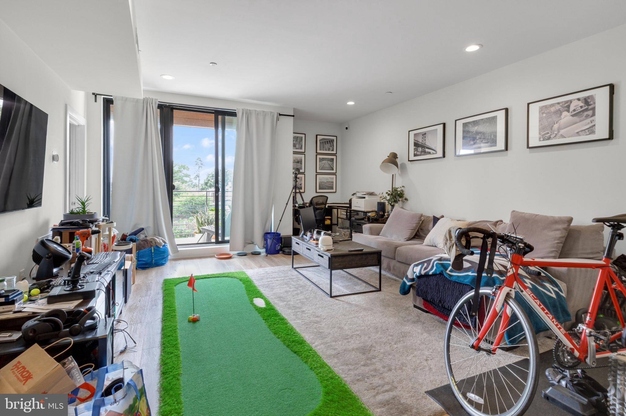 a living room with furniture a desk and a flat screen tv