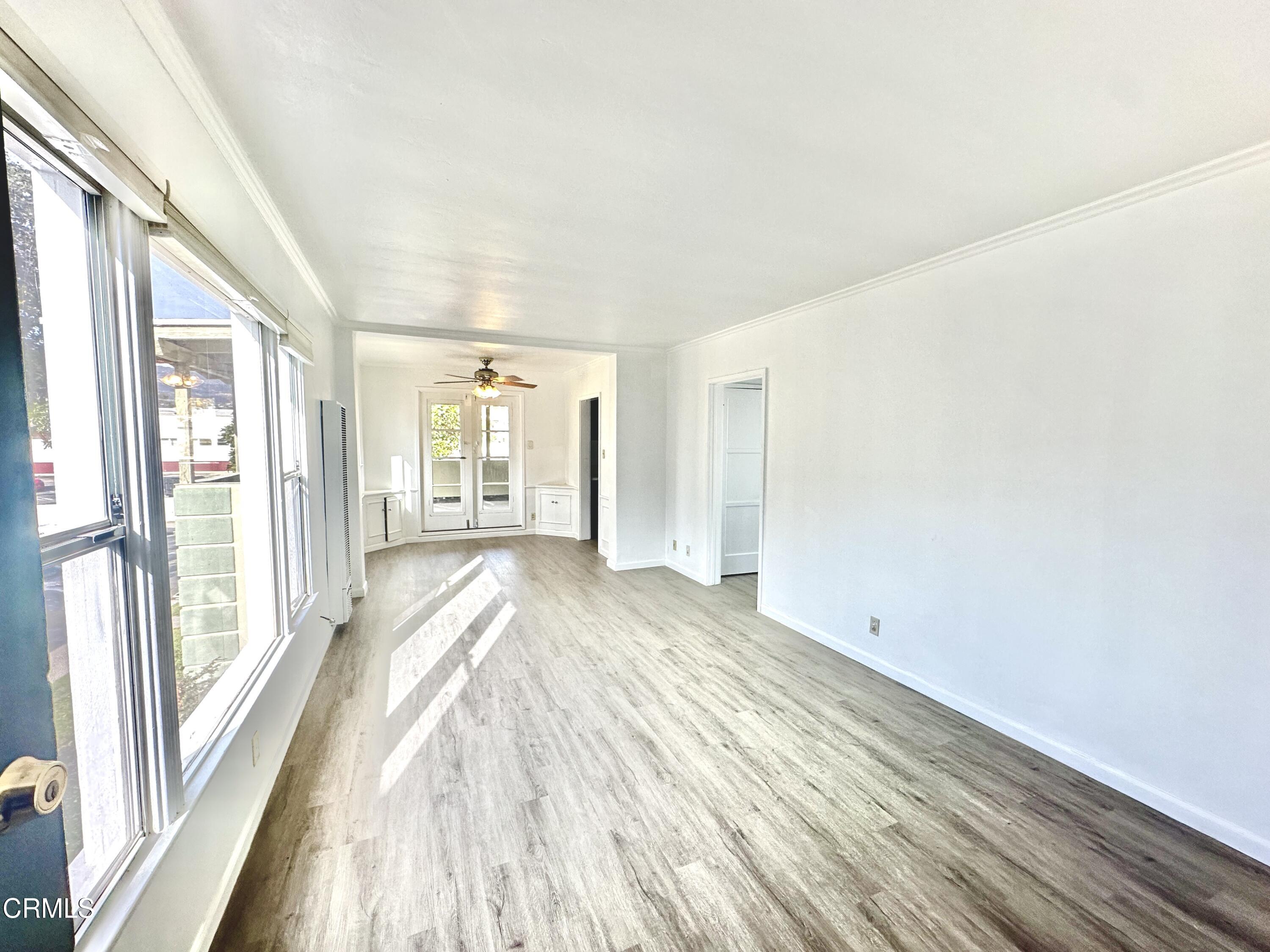 a view of an empty room with wooden floor and a window