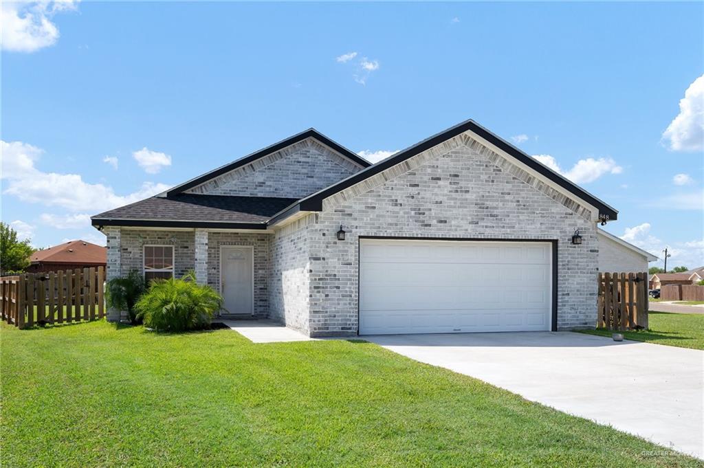 a front view of a house with a garden and garage