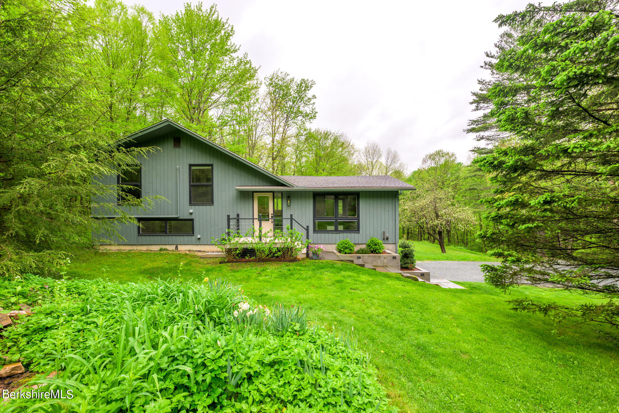 a front view of house with a garden and trees