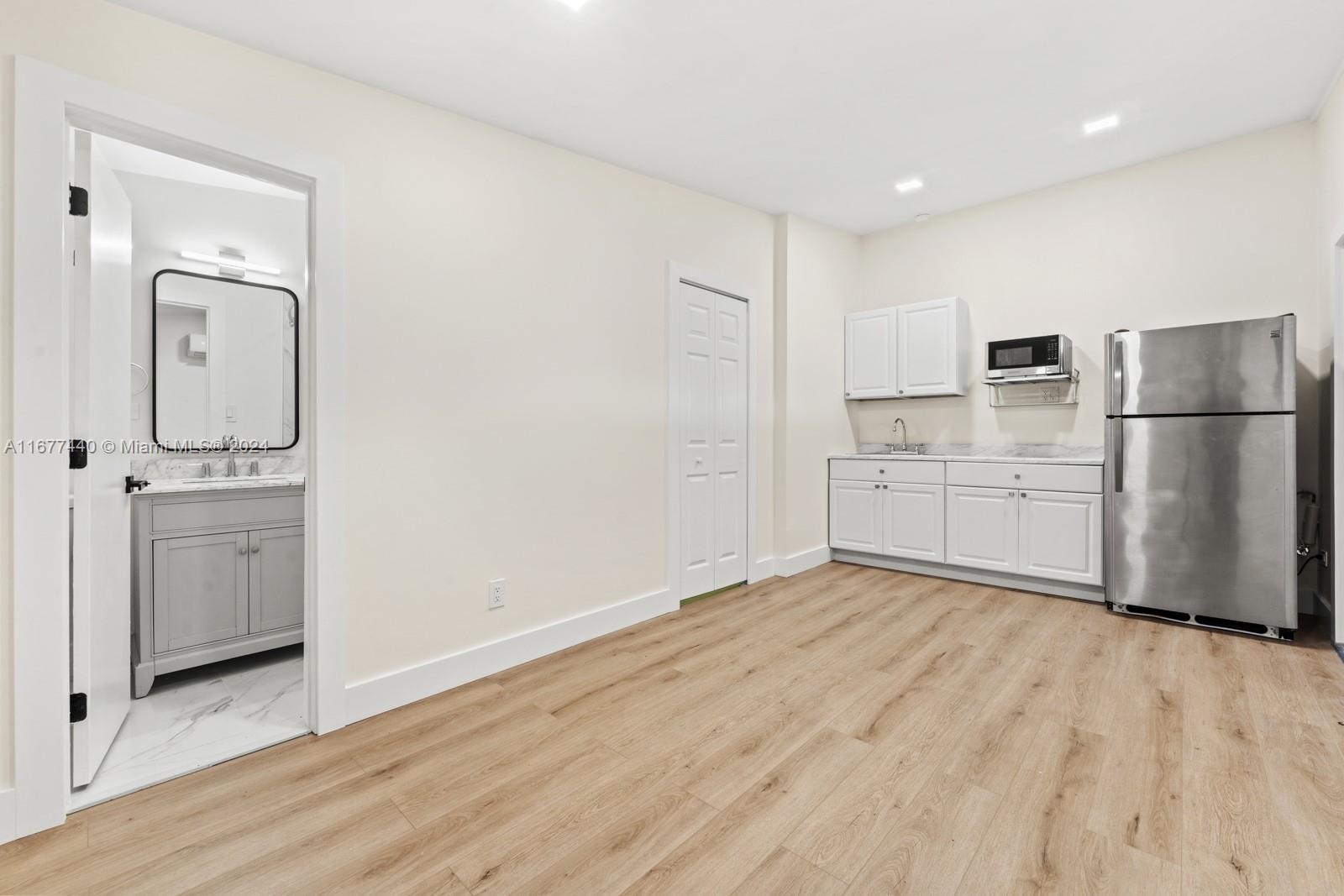 a view of a kitchen with a sink and dishwasher a refrigerator with white cabinets