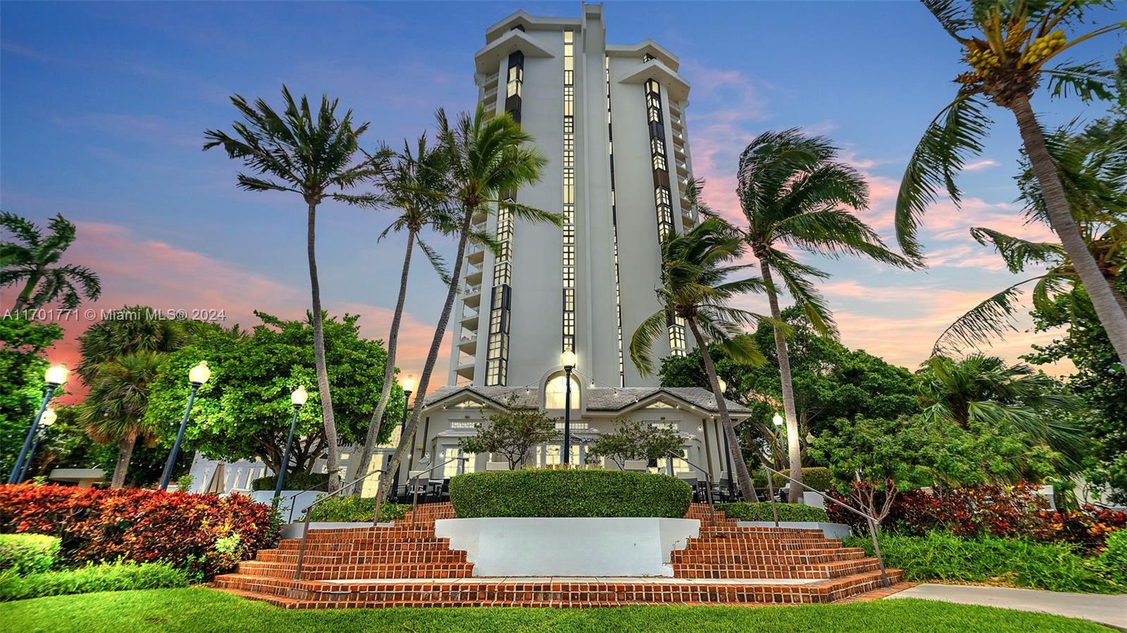 a front view of multi story residential apartment building with yard and green space