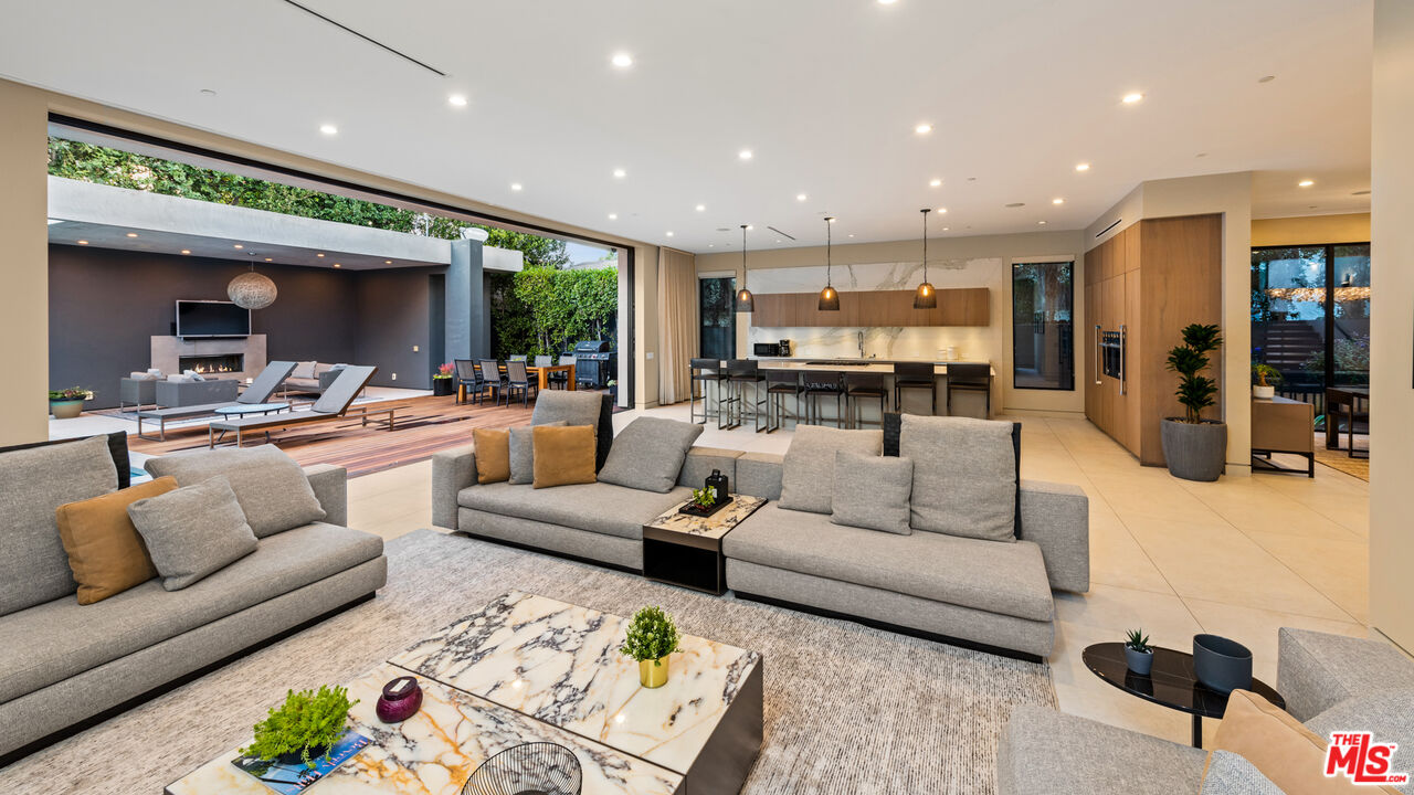 a living room with furniture kitchen view and a large window