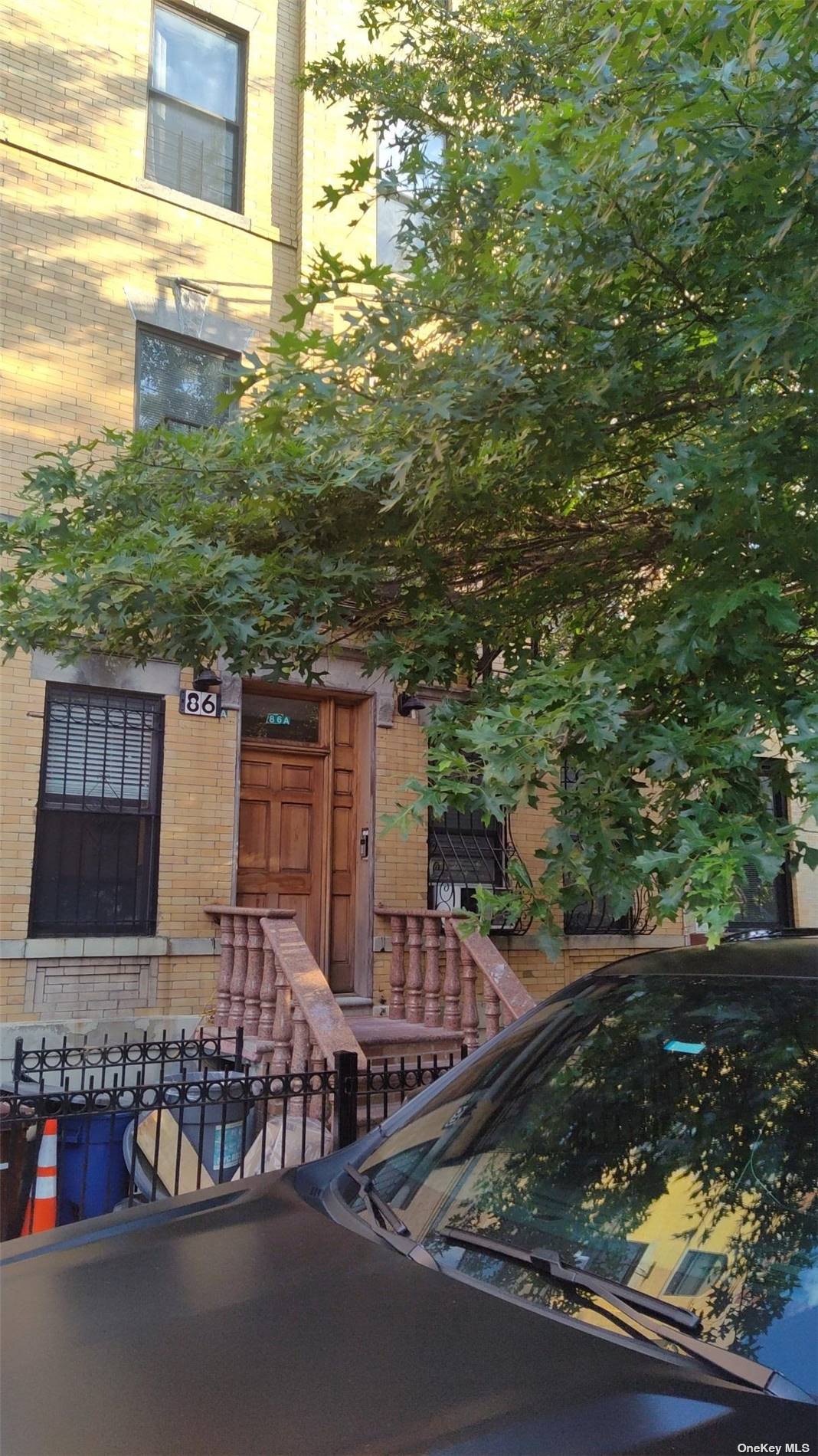 a view of a brick house with a large tree front of house