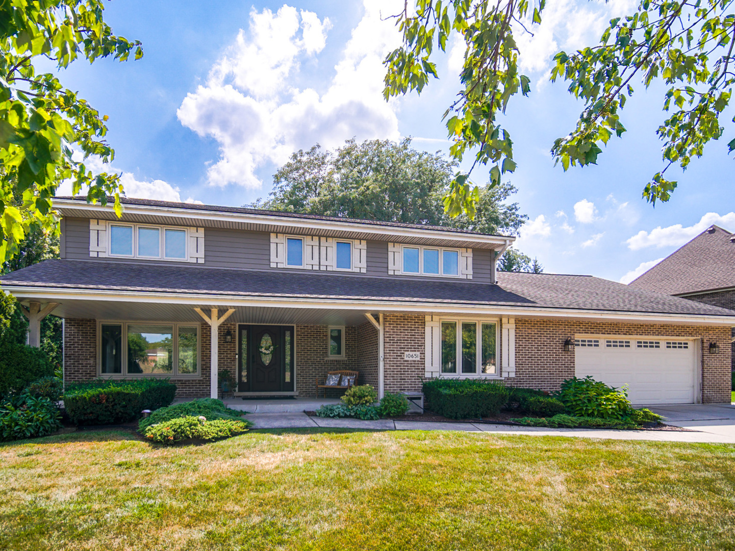 a view of a brick house with a yard large trees and a large tree