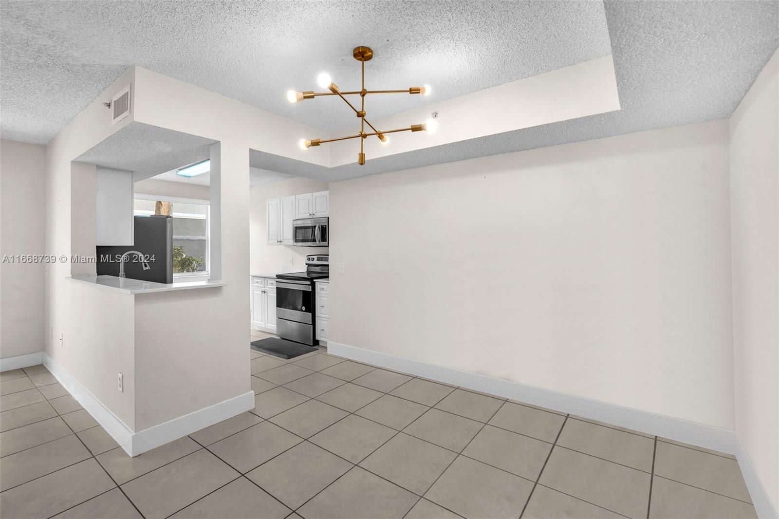 a view of a kitchen with a sink and dishwasher a refrigerator with white cabinets