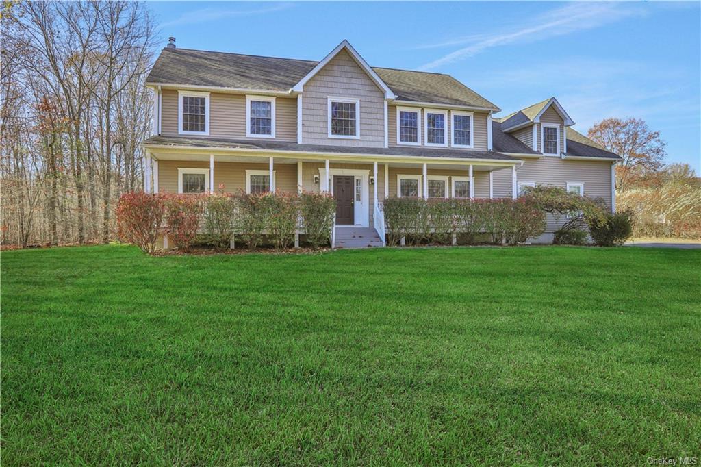 Colonial inspired home featuring covered porch and a front lawn